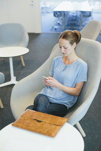 Young woman sitting in waiting area in office building