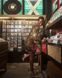Portrait of young woman standing in a record store wearing a glittery outfit