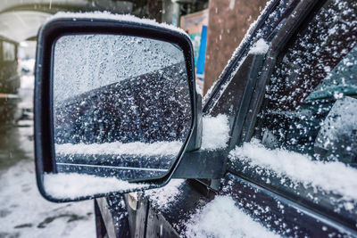 An iced car side mirror with snow. winter has come