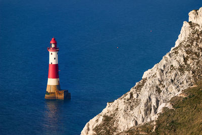 Lighthouse by sea against buildings