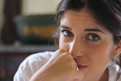 Close-up portrait of woman with hand covering mouth at home