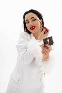 Portrait of a beautiful girl applying a makeup on a white background