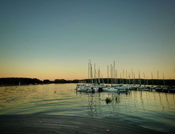 Sailboats in marina at harbor against clear sky