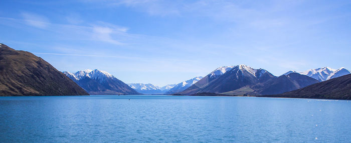 Scenic view of lake and mountains against blue sky