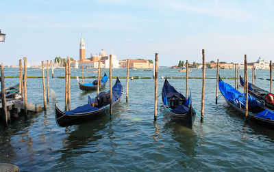 Boats moored in river with city in background