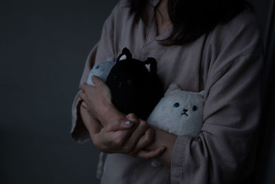 Midsection of woman holding toys against gray background