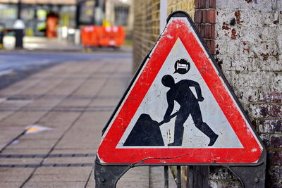Men at work sign by wall on footpath