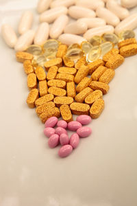 Mix of gold, pink and white gel capsules of vitamin b, vitamin e, vitamin d, biotin and co q-10 