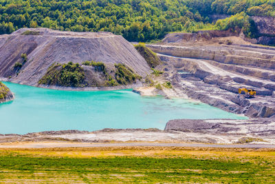 Mine pit lake in the old marl quarry, yellow dump truck on the shore of sint-pietersberg