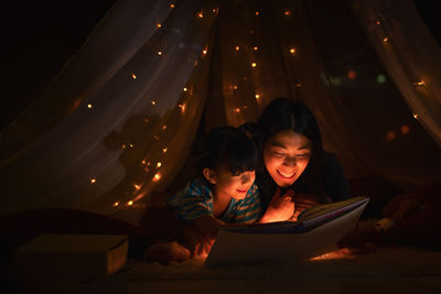 High angle view of siblings and woman using smart phone at night