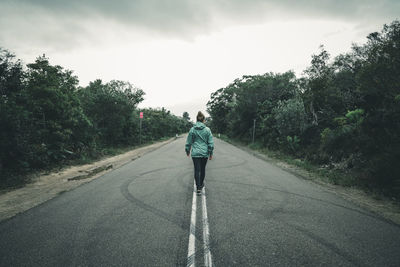 Rear view of young woman walking on highway