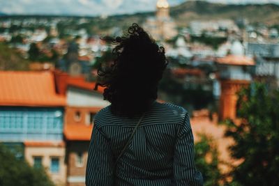 Rear view of woman standing against buildings in city