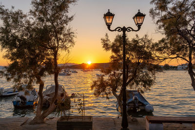 Street light by lake against sky during sunset