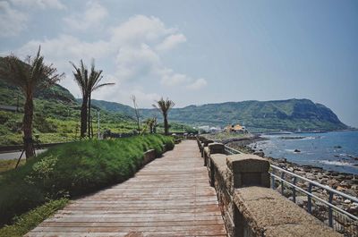 Footpath by sea against sky