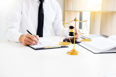 Midsection of lawyer working on desk