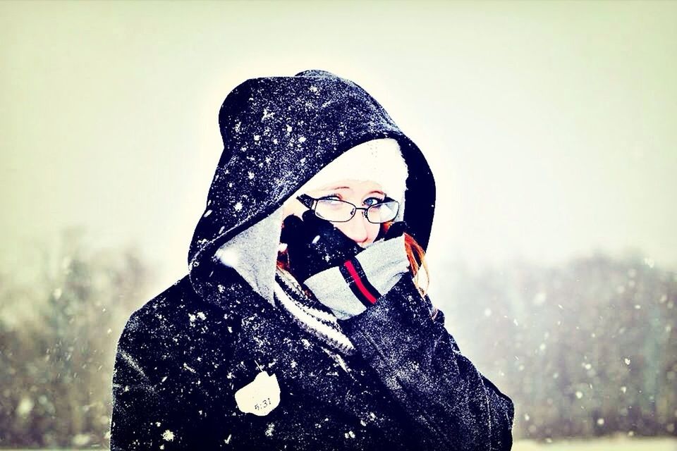 lifestyles, leisure activity, young adult, casual clothing, person, standing, young women, front view, looking at camera, three quarter length, warm clothing, portrait, winter, waist up, focus on foreground, holding, hat, hood - clothing