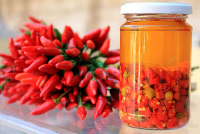 Bunch of chili peppers and pickle bottle on table