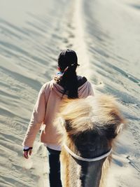 Rear view of woman walking with camel on sand dune in desert