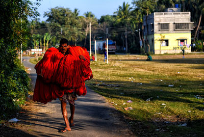 Man carrying fabrics while walking on footpath