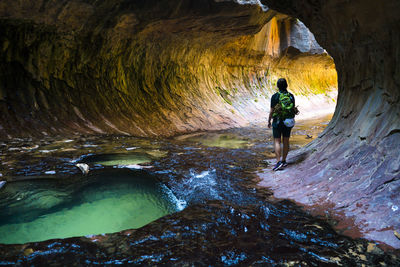 Rear view of hiker walking in cave