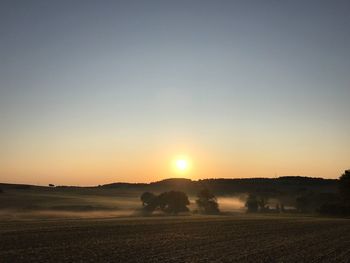 Scenic view of field against clear sky during sunset