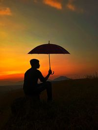 Silhouette people standing on land against sky during sunset