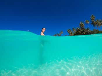 Portrait of mature woman swimming in sea against clear blue sky during sunny day