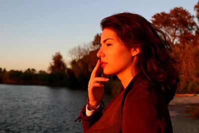 Young woman looking at lake during sunset