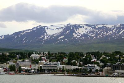 Scenic view of townscape by mountains against sky