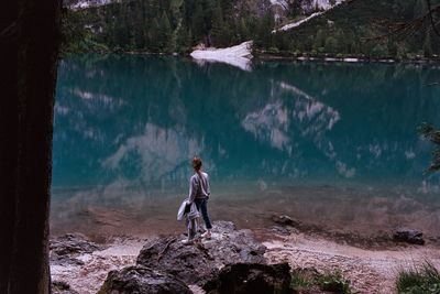 Full length side view of man standing by lake in forest