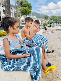 Side view of children sitting at beach