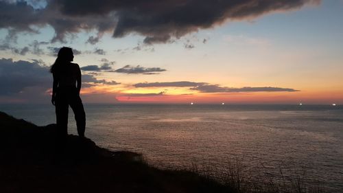 Silhouette man looking at sea against sky during sunset