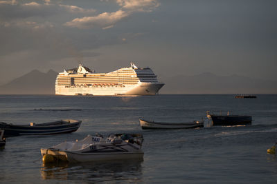 Boats in sea against sky during sunset