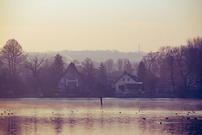 Houses by trees against clear sky during winter