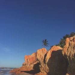Rock formations at seaside against blue sky