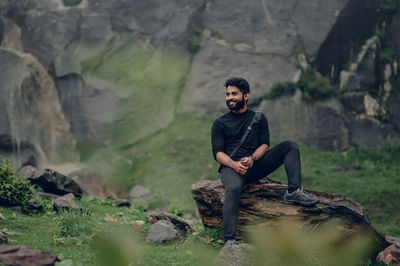 Young man sitting on rock