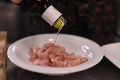 Midsection of person pouring cooking oil in fish bowl at kitchen