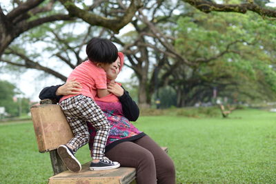 Boy kissing mother sitting on park bench