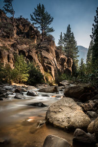 Stream flowing through rocks against sky