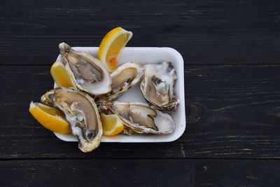 High angle view of oyster and lemons in tray on table