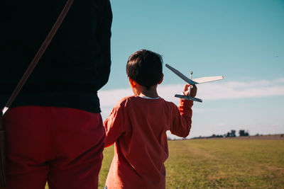 Rear view of mother and son on land against sky