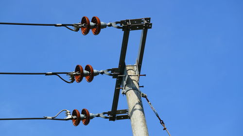 Low angle view of telephone pole against clear blue sky