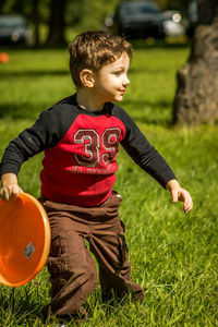 Boy playing with plastic disc on grassy field