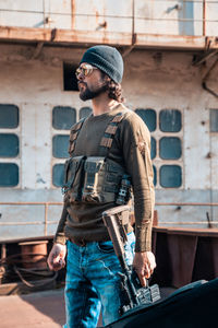 Young man wearing hat standing against wall