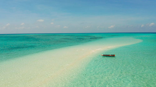 Sandy beach with tourists among turquoise waters and coral reefs. mansalangan sandbar. 
