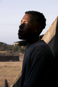 Portrait of young man looking away against sky