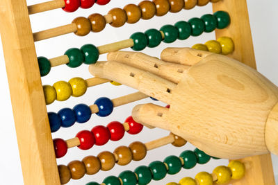 Close-up of wooden hand on abacus against white background