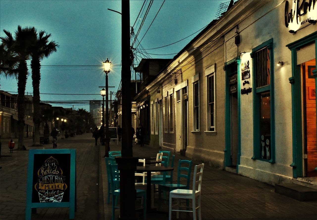 ILLUMINATED STREET AMIDST BUILDINGS AT NIGHT