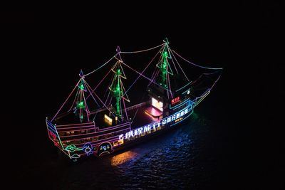 Illuminated ship sailing in sea against sky at night