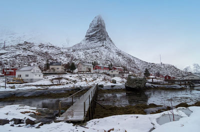 Snow covered houses by buildings against sky norway